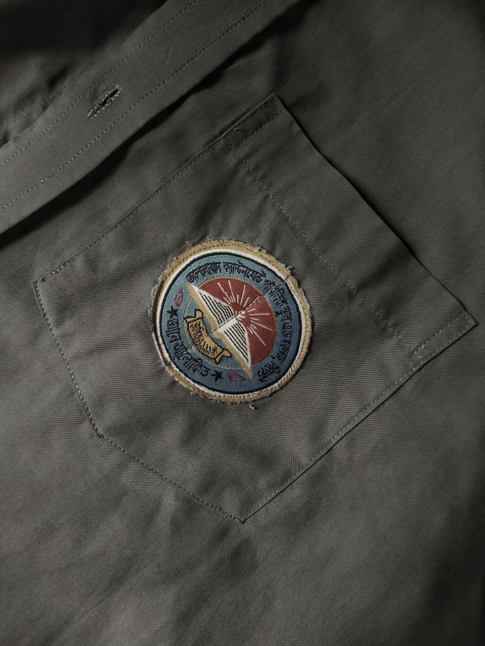Close-up of a vintage shirt pocket featuring an embroidered patch with a sunburst design.