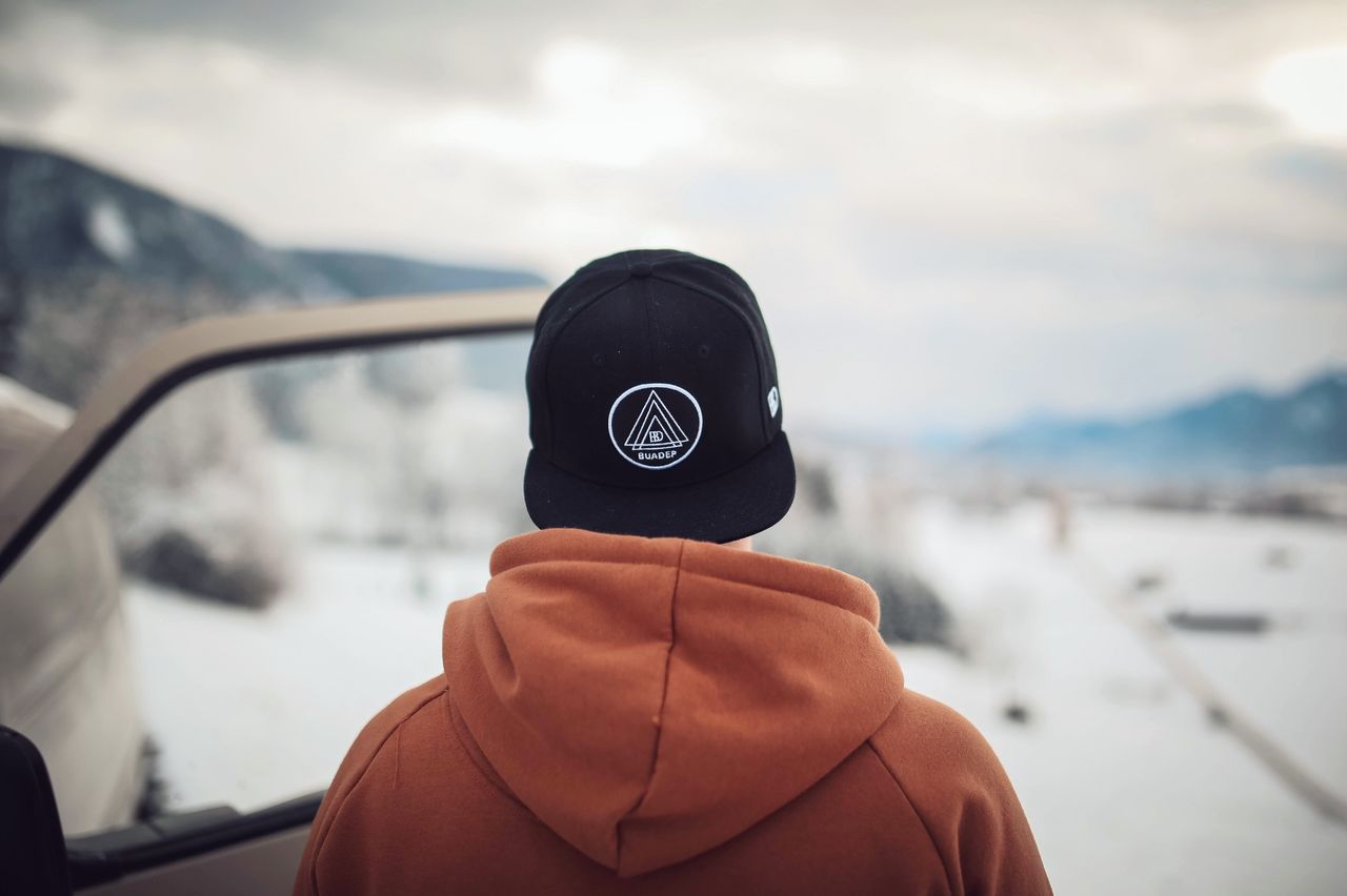 A person stands by a car in snowy Ohlstadt, Germany, admiring winter mountains.