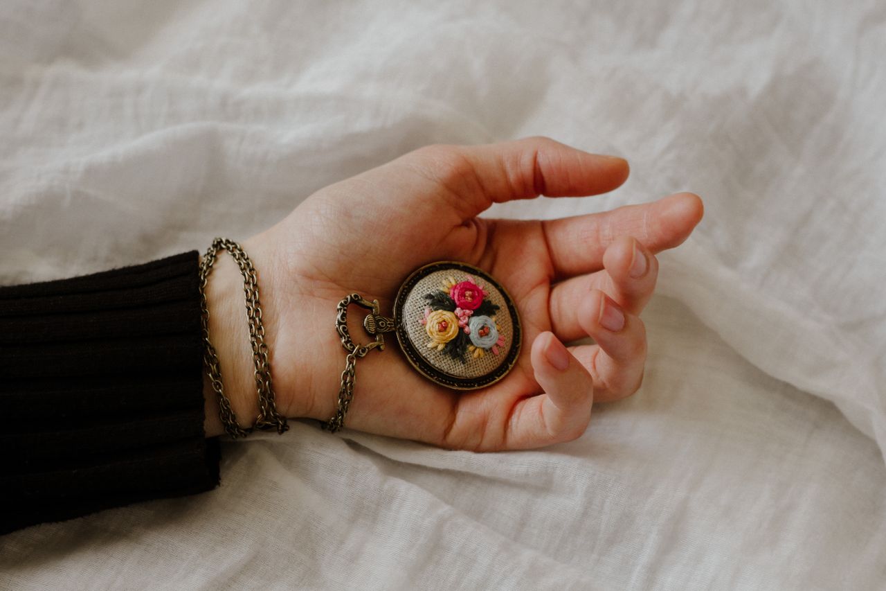 Top view of crop anonymous female with vintage chain watch on hand on white fabric